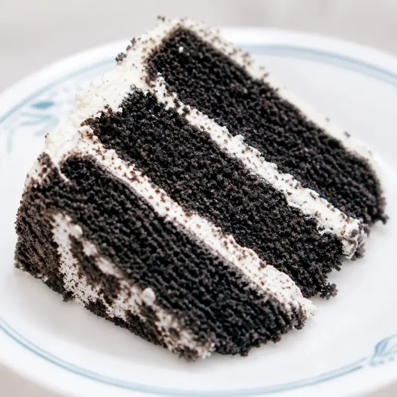 A slice of Easy Black Sesame Cake showcasing striking dark layers with a rich black color.